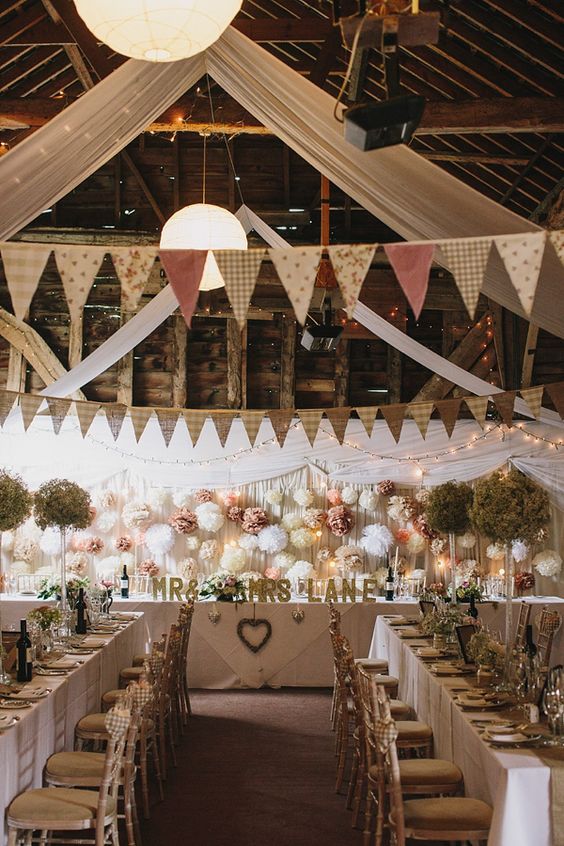 rustic wedding barn styling including draping, bunting, pom poms and fairy lights