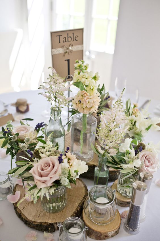 centrepiece of rustic tree slices with jars of pink flower stems