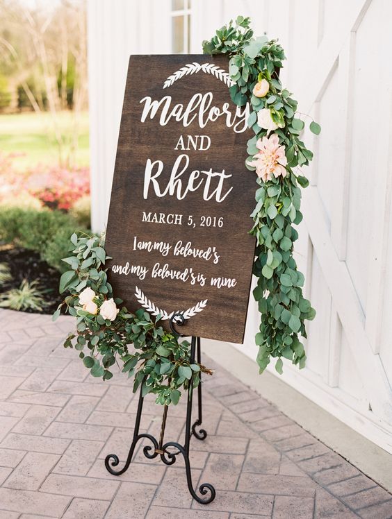 rustic wooden wedding sign covered in eucalyptus garland via becca lea