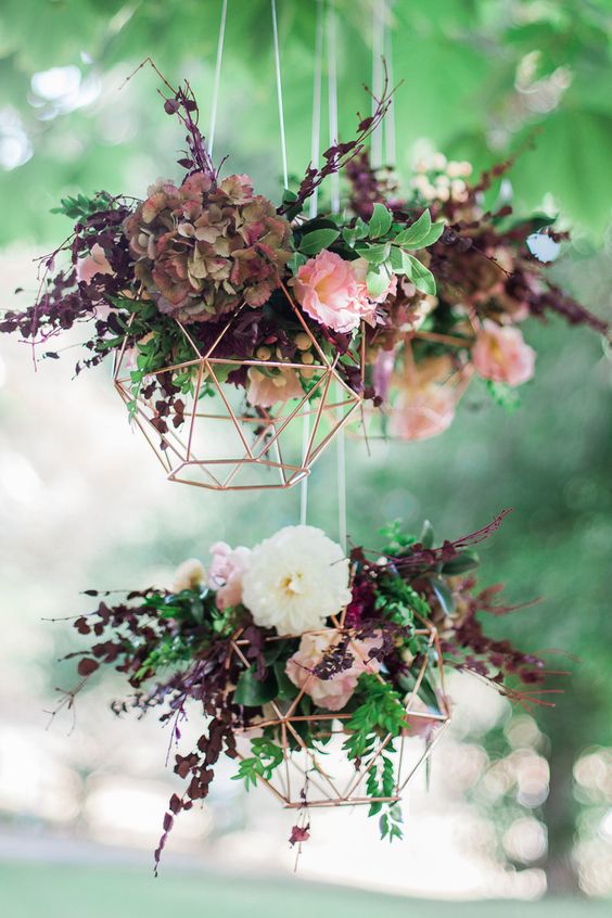 Geometric copper wedding reception hanging feature with burgundy flowers via Blush & Mint Photography