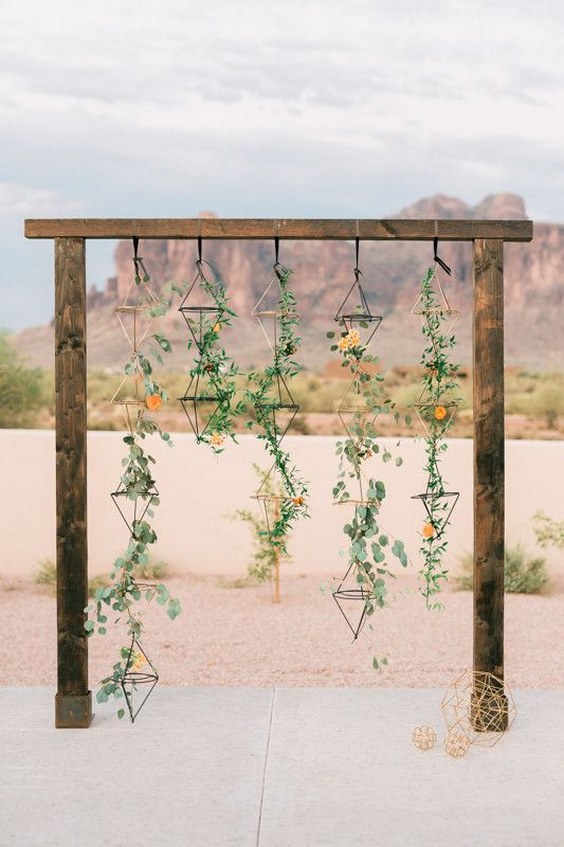Geometric desert wedding arbor with hanging greenery and color-coordinated flowers wedding arch