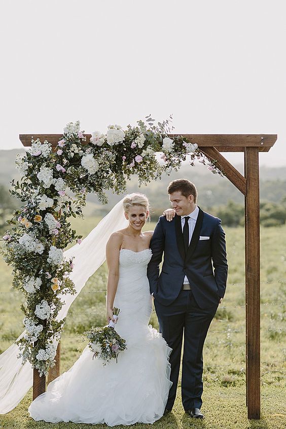 Stunning wedding arch with cascading floral arrangement in a neutral palette via heart and colour