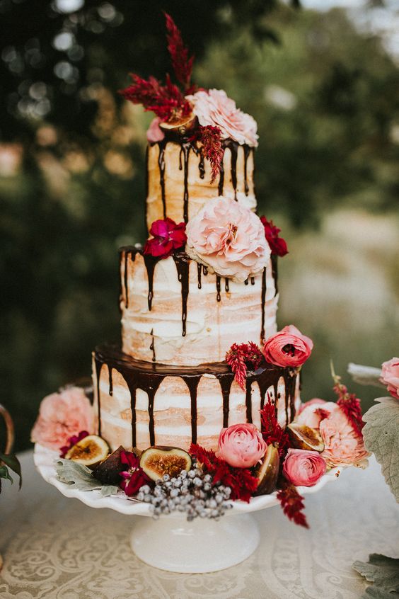 flower topped naked wedding cake with chocolate drizzle