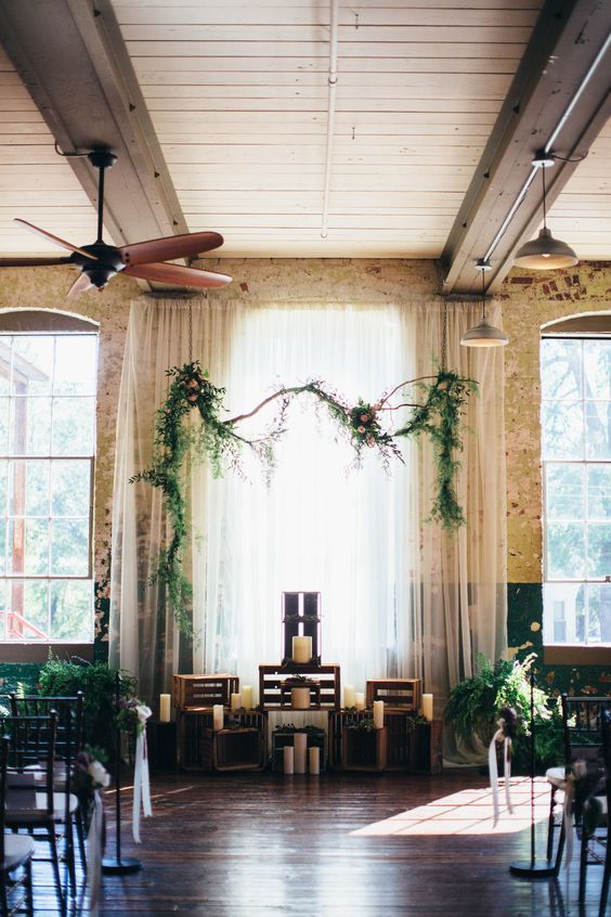 Industrial wedding ceremony, indoor, wooden crates, large white candles, greenery