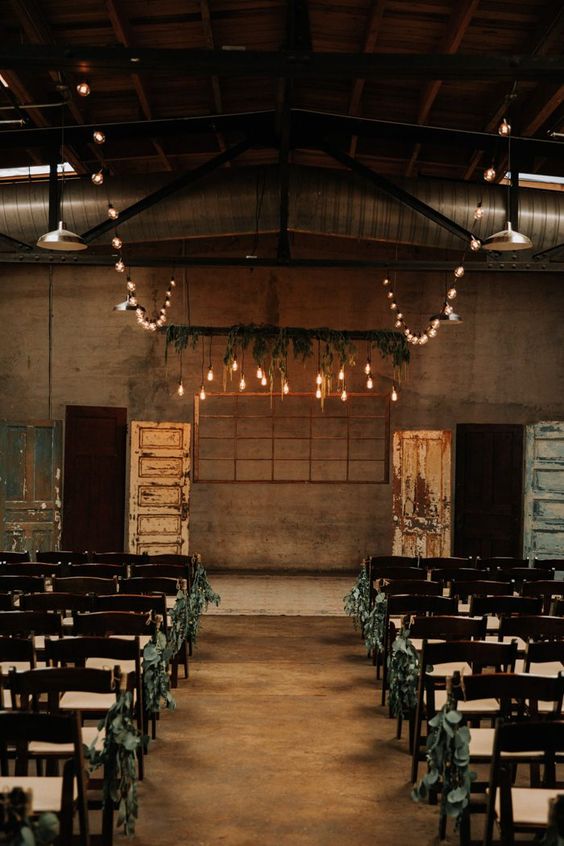Romantic ceremony in an industrial venue with dreamy cafe lights and an abundance of greenery