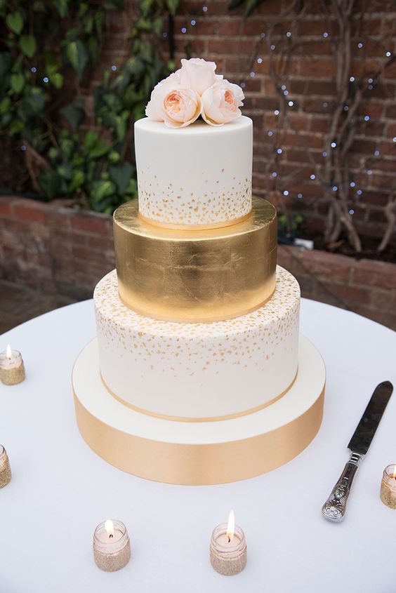 elegant gold and white wedding cake with floral topper