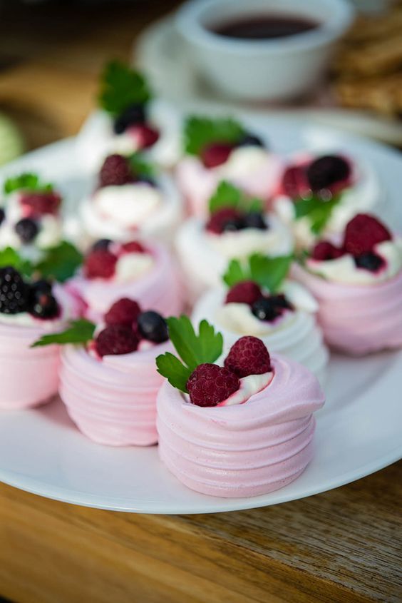 pink and white pavlova mini dessert with fresh whipped cream and berries