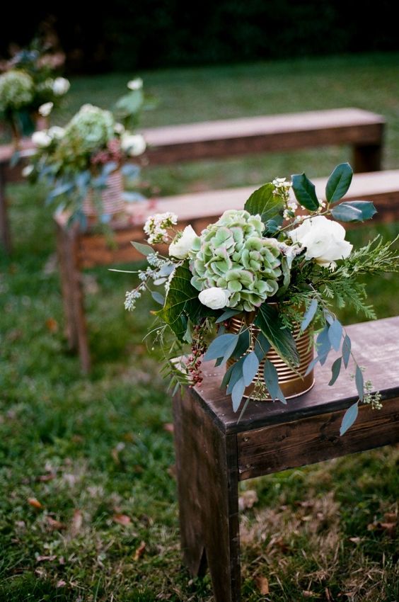 rustic aisle markers flowing with greenery and flowers against cool copper