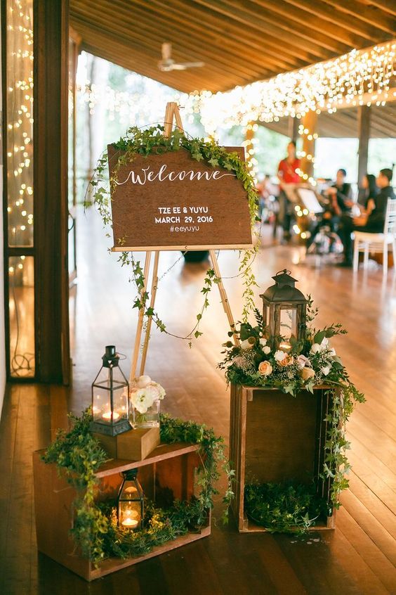 rustic wooden creat lantern and greenery welcome sign