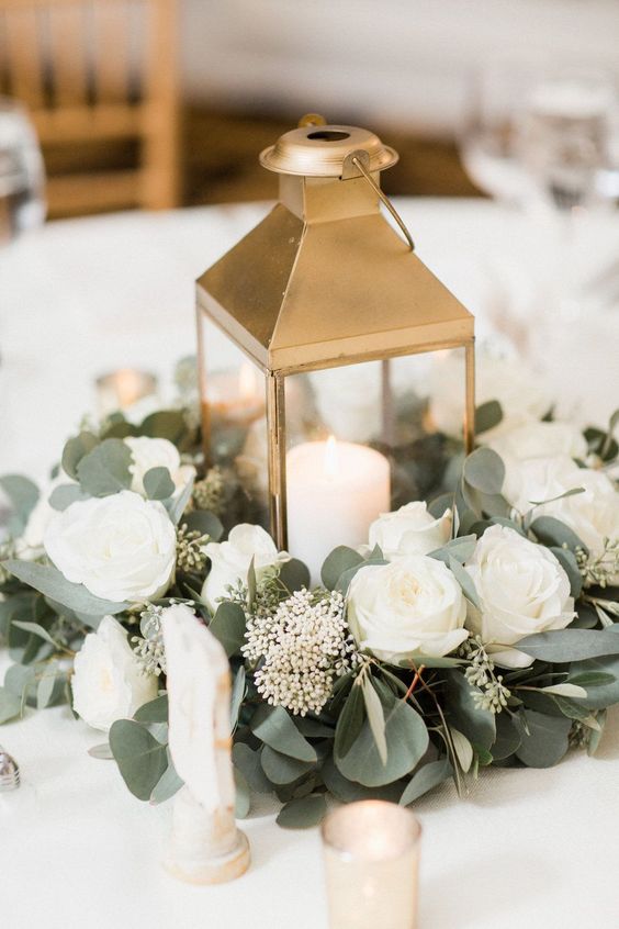 gold lantern centerpiece surrounded by white garden roses and eucalyptus