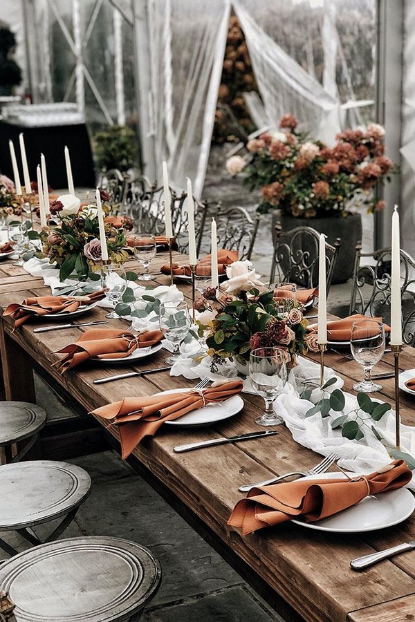 rust wedding color reception under transparent tent with white tablerunners candles and flowers 