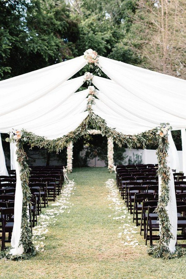 Outdoor wedding ceremony white fabric and greenery arches