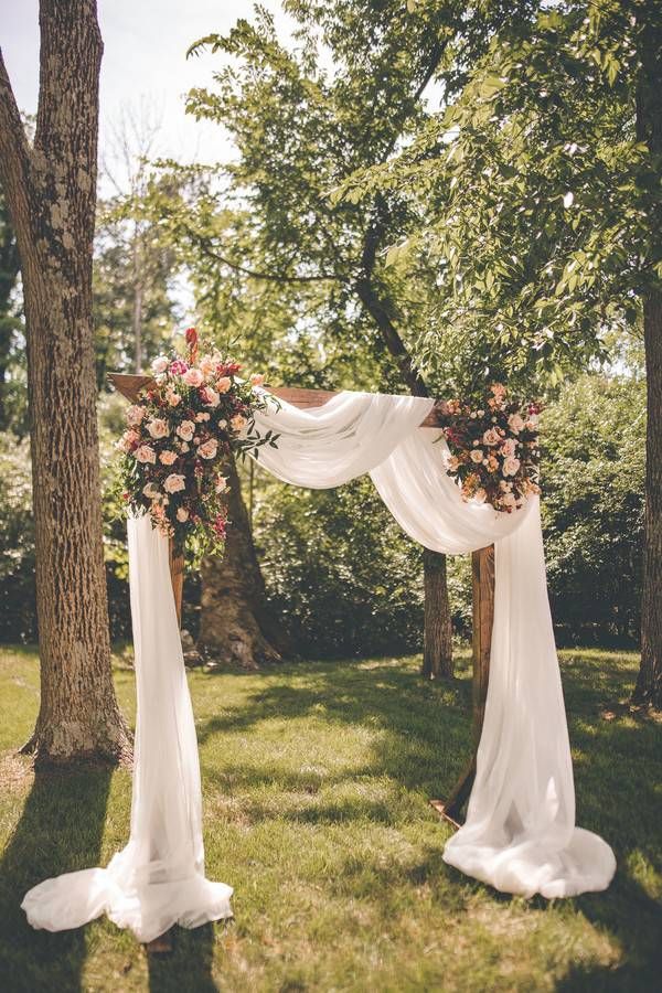 romantic wooden archway with load of draping fabric and pink flowers