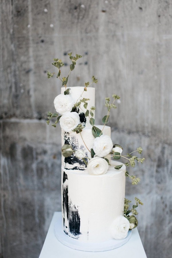 black and white buttercream wedding cake with greenery leaves