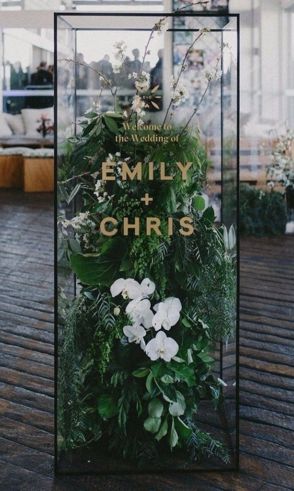 glass-box installation filled with orchids and fresh ferns