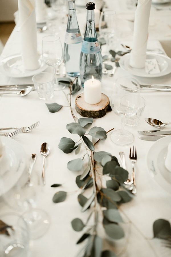 minimalist wedding reception table with greenery and candles