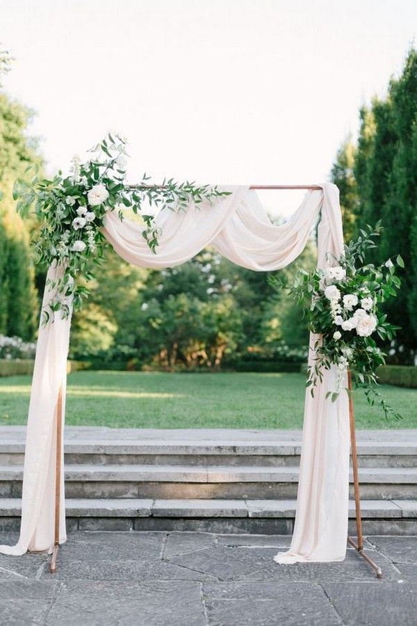 outdoor copper wedding arch with greenery and ivory draping