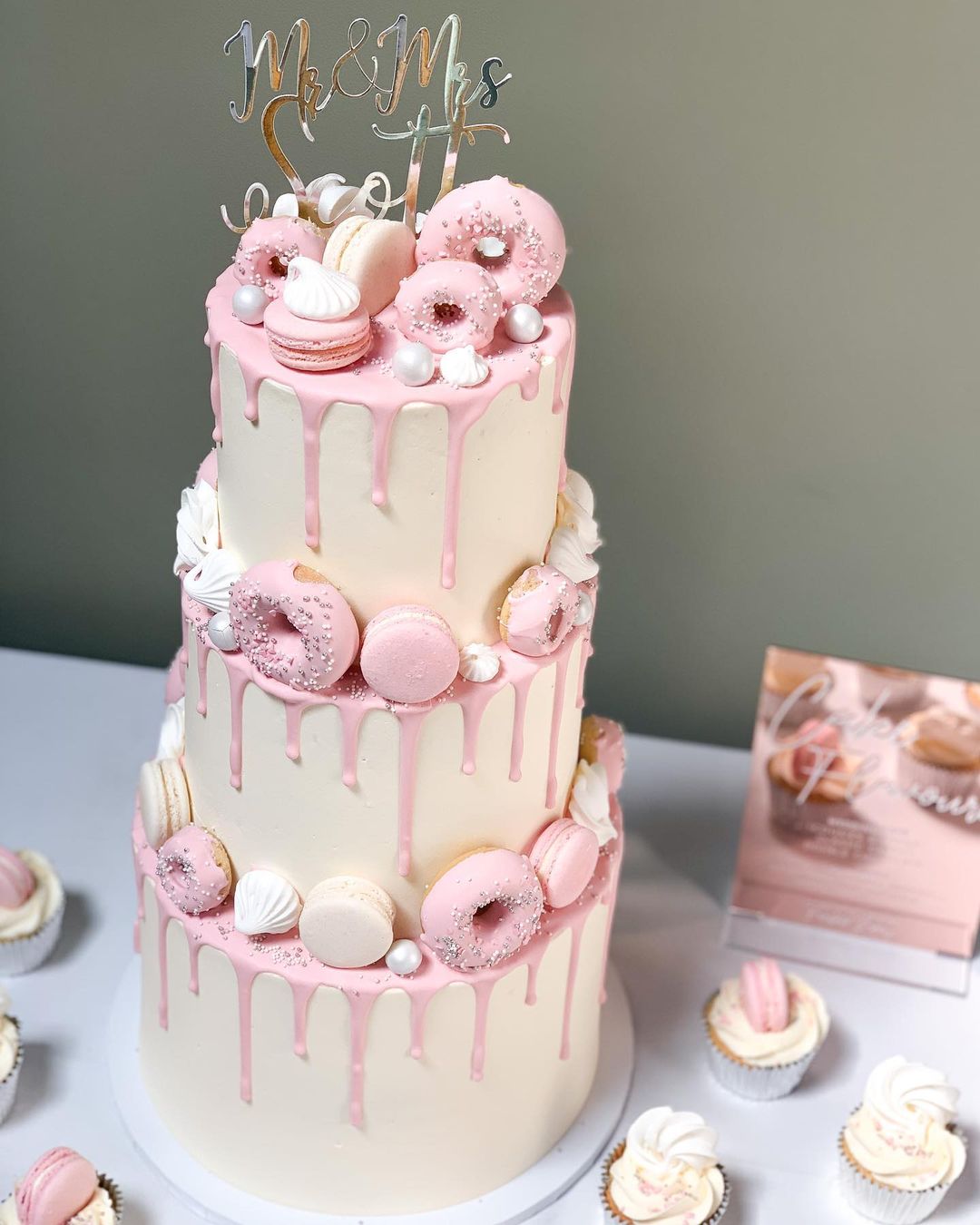 3 three tier pink drip wedding cake with pink donuts and gold mirror name cake topper via frostbitebakery