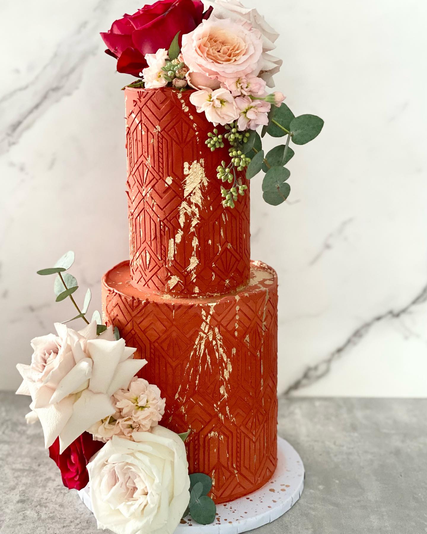 Red stencilled wedding cake with roses