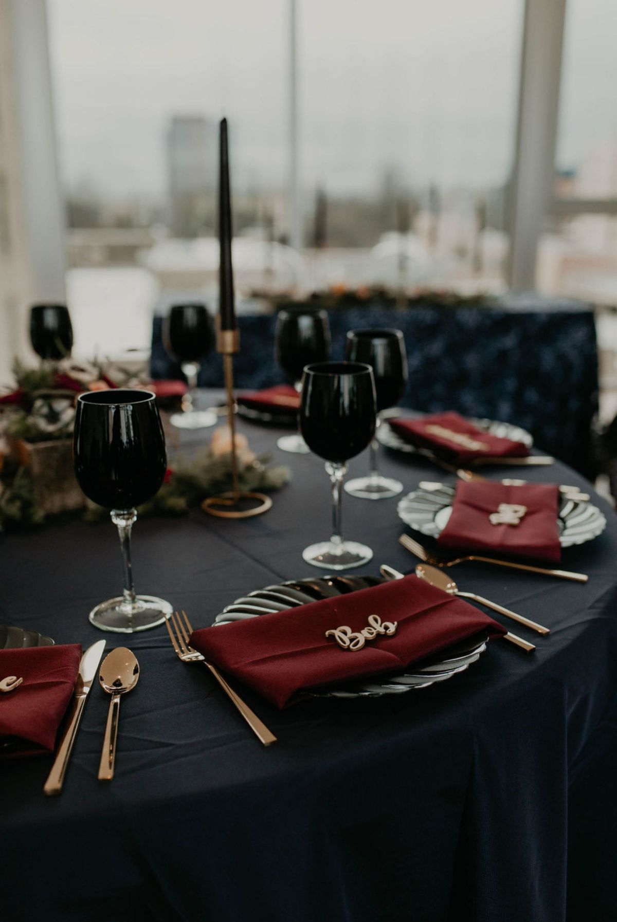 black round wedding table with burgundy napkins and black glasses