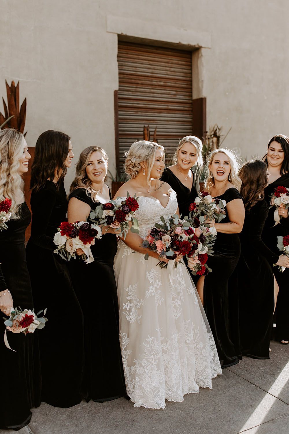 bridesmaids in black dresses with burgundy bouquets