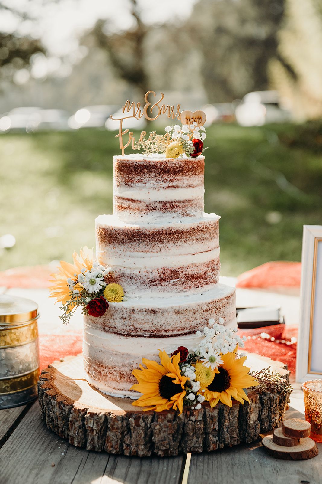 rustic three semi-naked red velevt wedding cake with sunflowers and tree stump stand