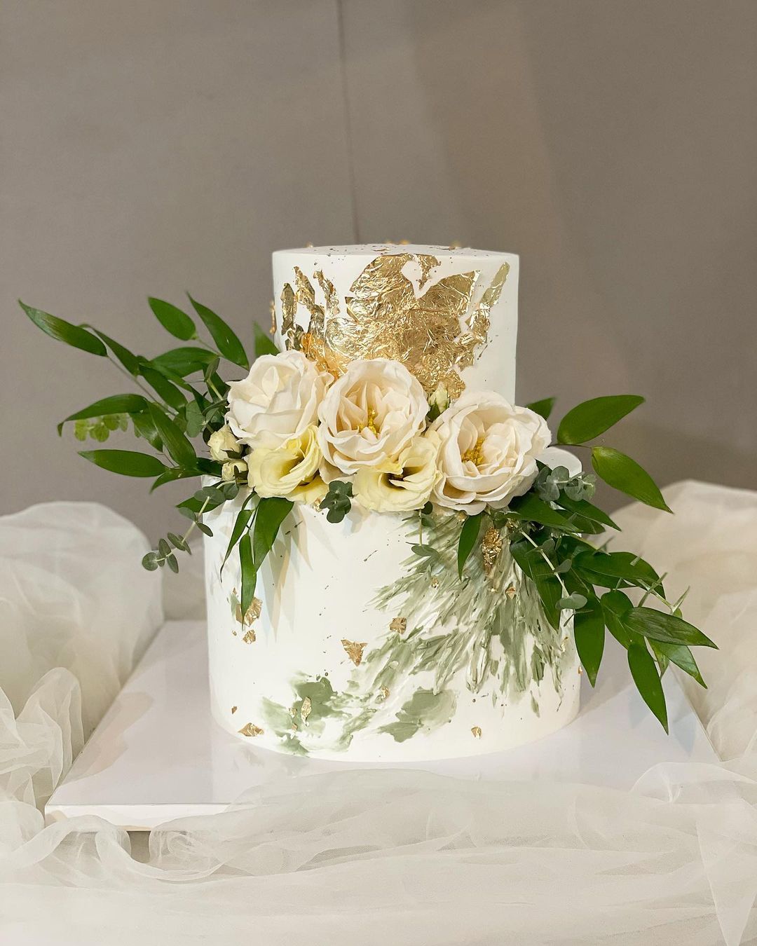 simple 2 tier wedding cake with gold flakes via negin_cake_studio