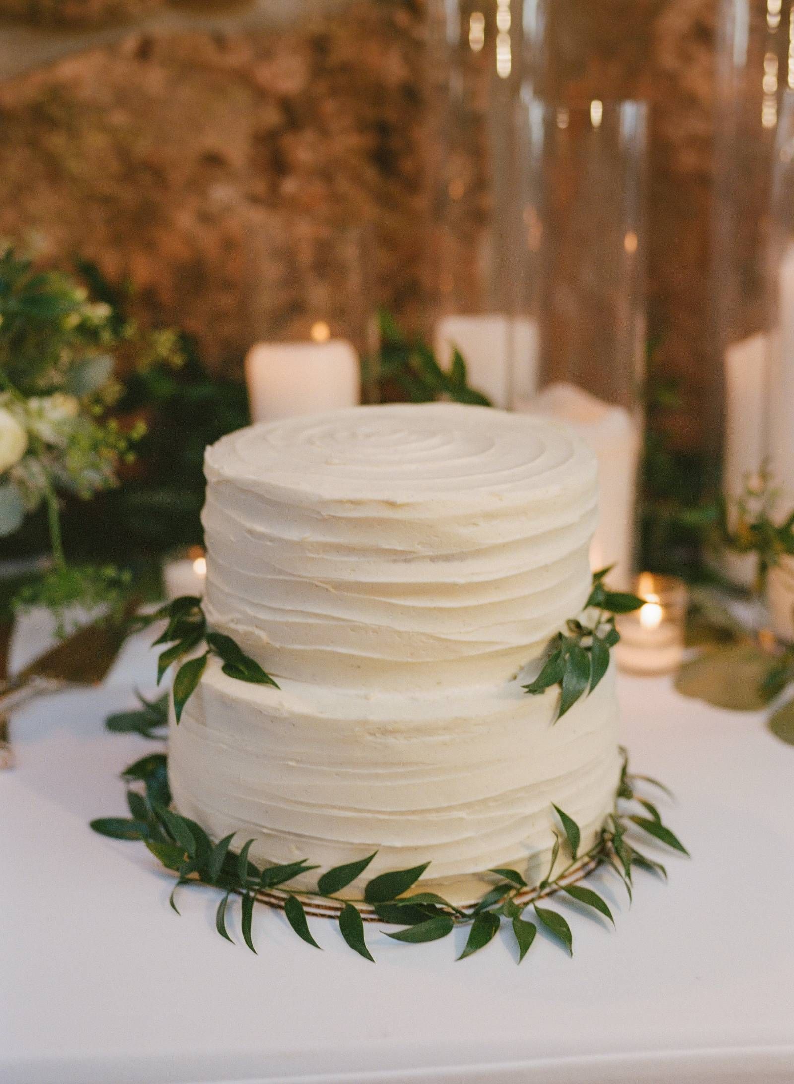 simple two tier buttercream wedding cake with greenery