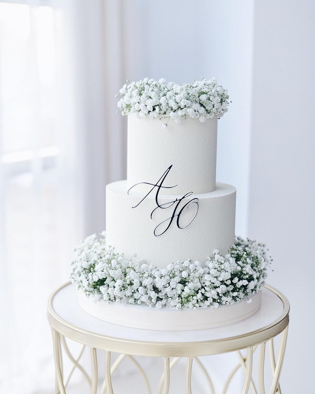 simple white matte forested 2 tier wedding cake with babys breath via viaboni_bakery