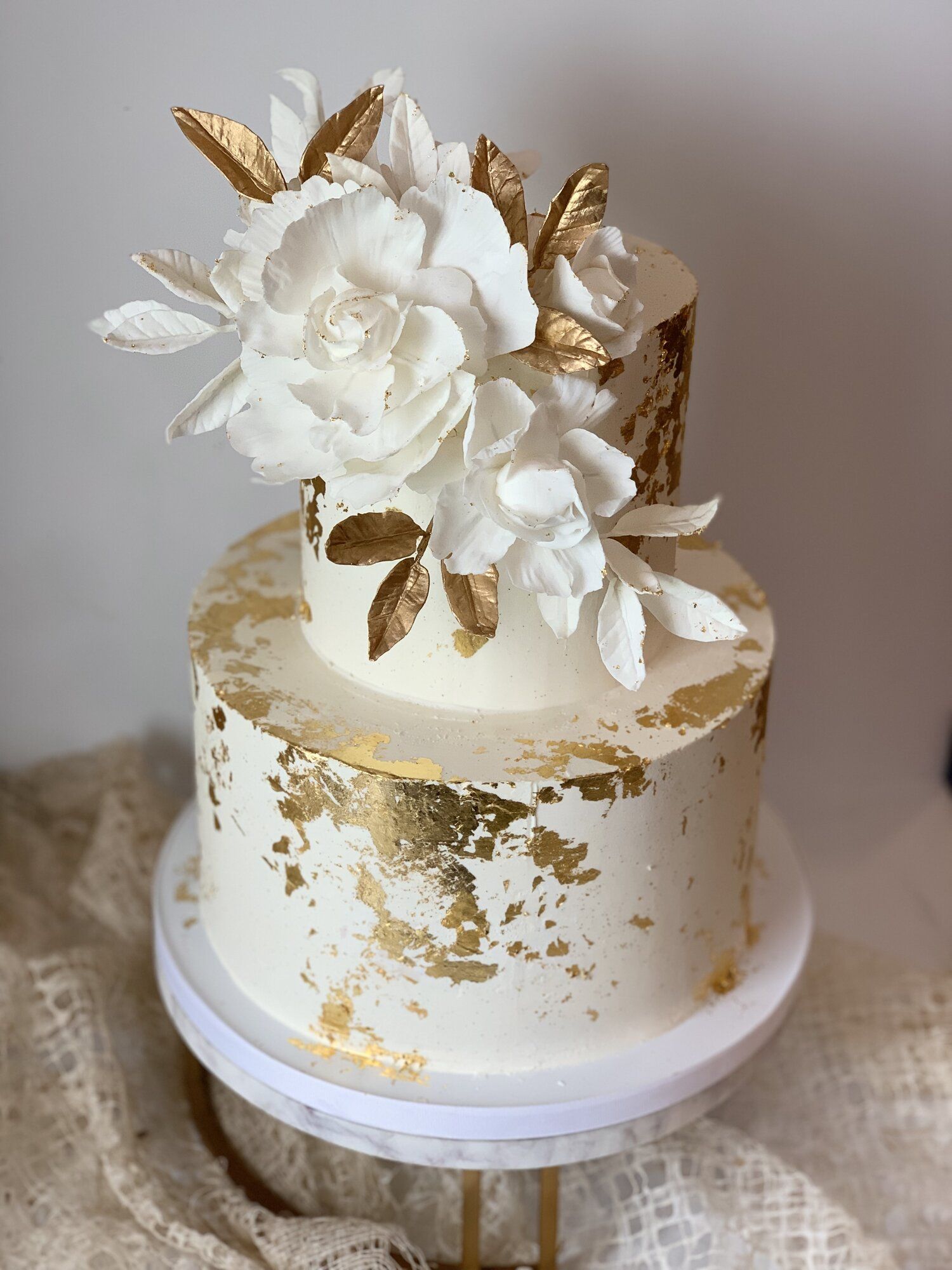 vintage white wedding cake with gold flakes and sugar flower