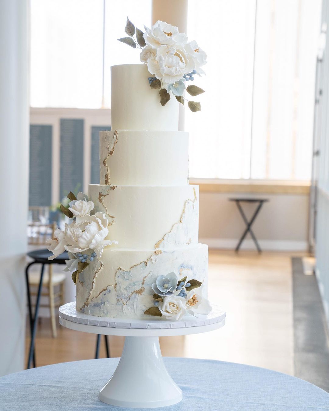 four tier elegant light blue wedding cake with gold paint via delishcakery