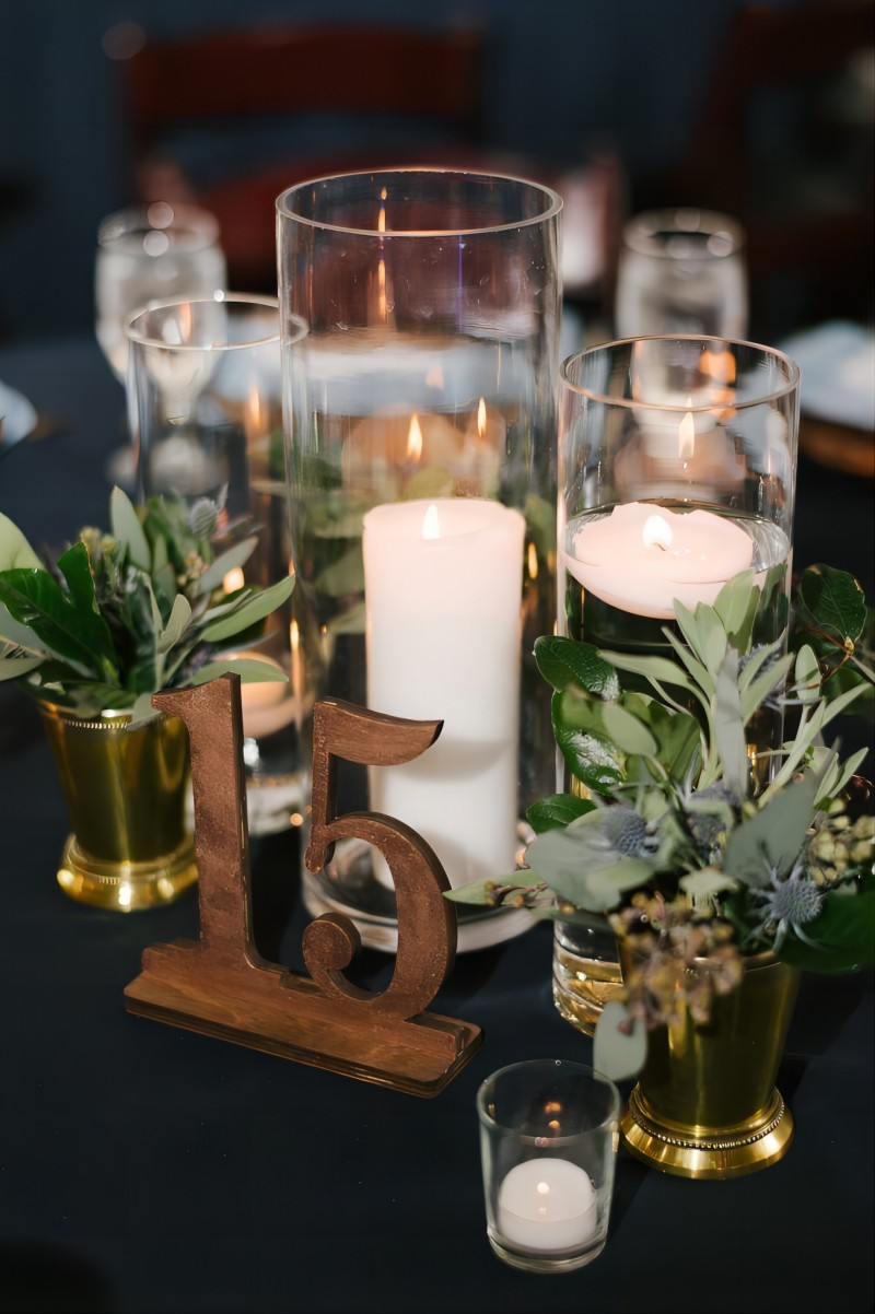 candles and greenery with wooden table number wedding centerpiece