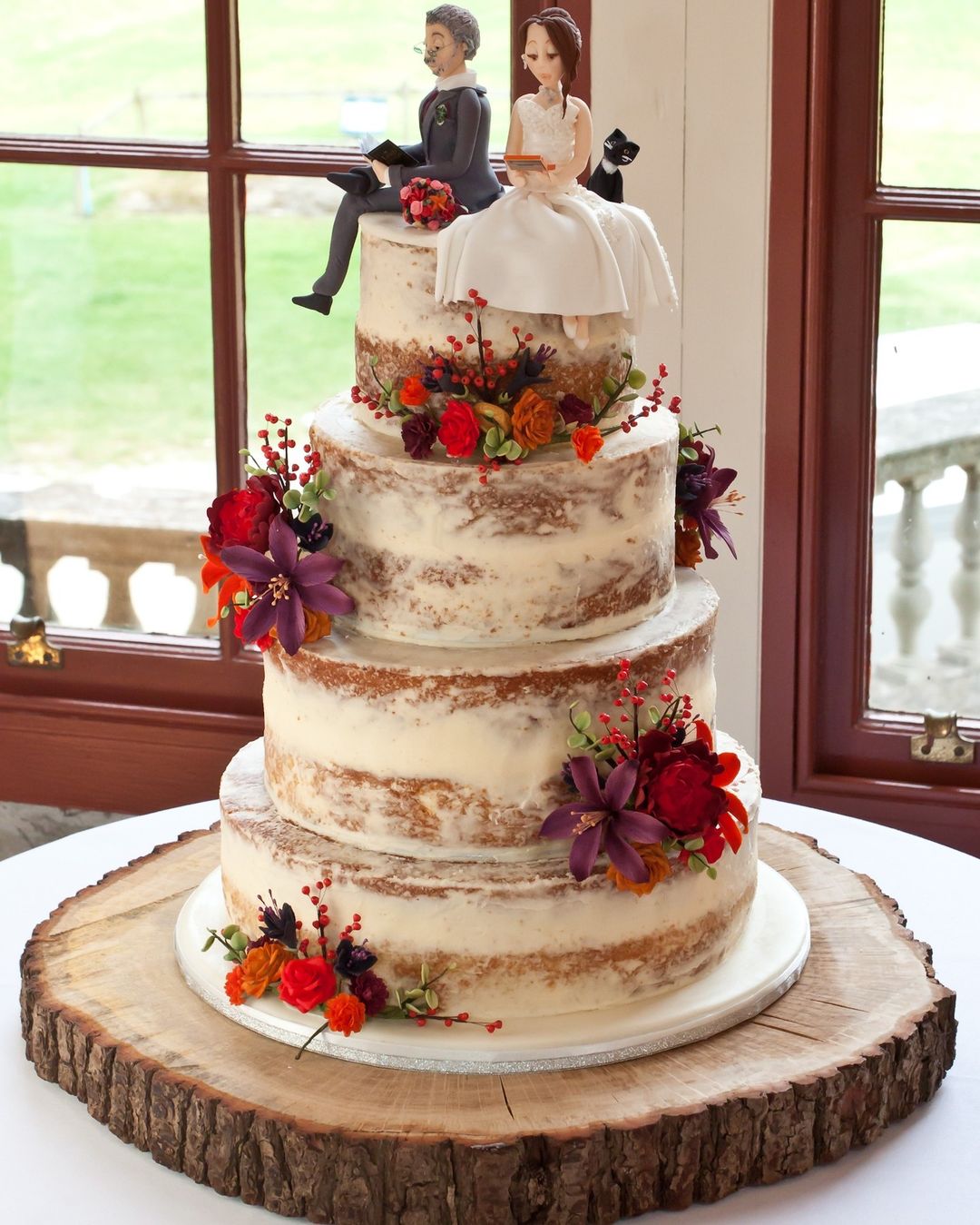 country fall semi-naked 3 tier wedding cake with red flowers and cute couple topper via fondofcakesuk_
