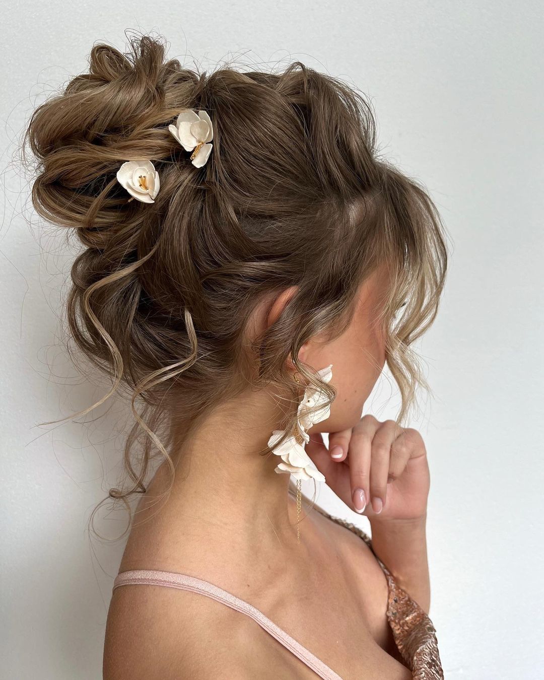 messy high bun updo hairstyle with flowers via jeny.stylist