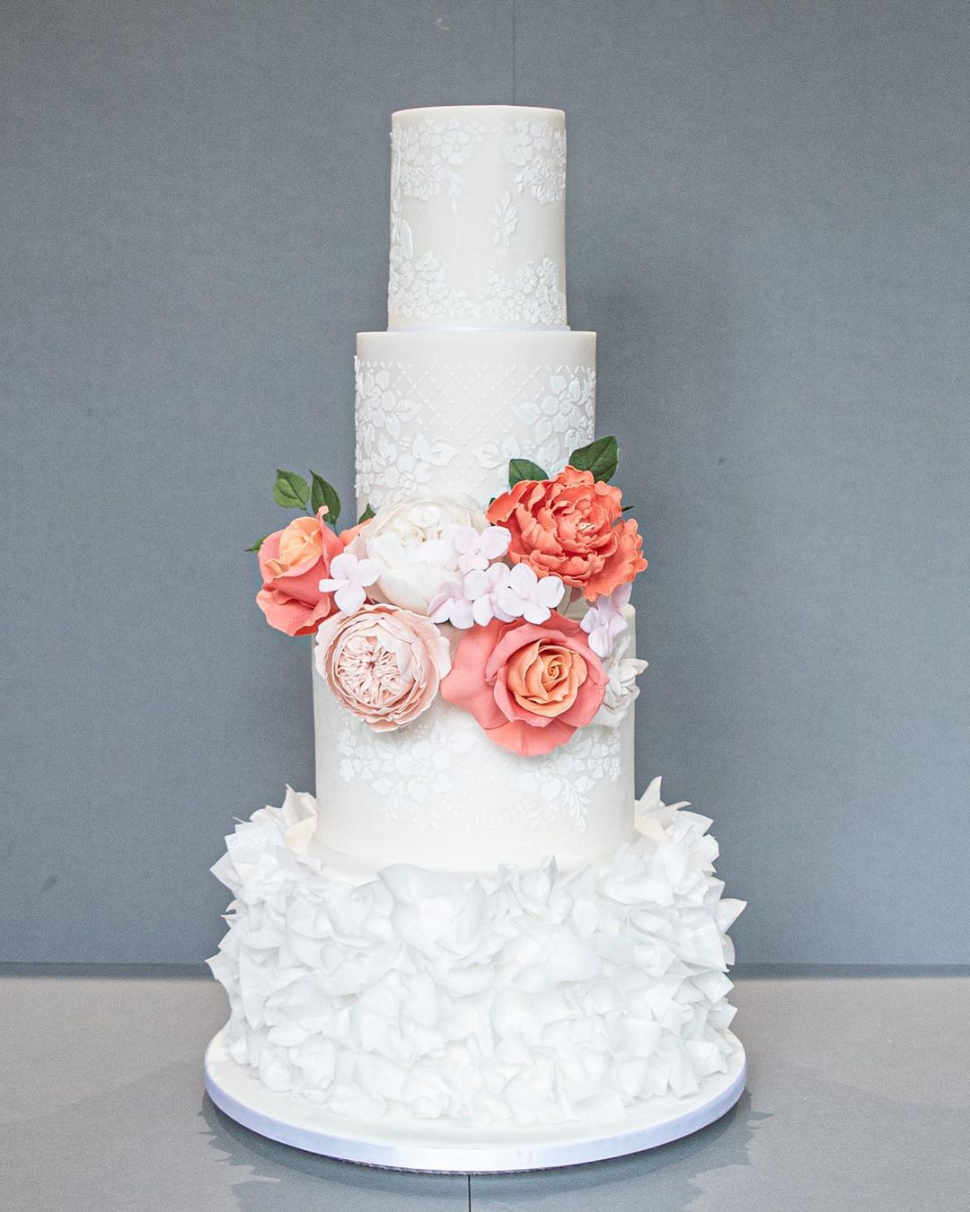 vintage 4 tier lace and ruffles wedding cake with coral flowers via cakedaydreams