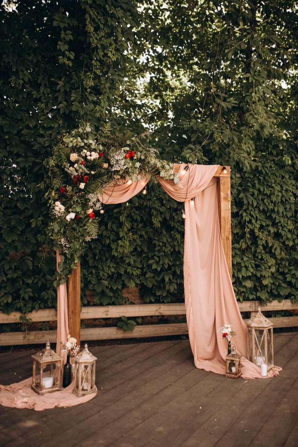 dusty rose rustic backyard outdoor wedding arch with fabric drapes