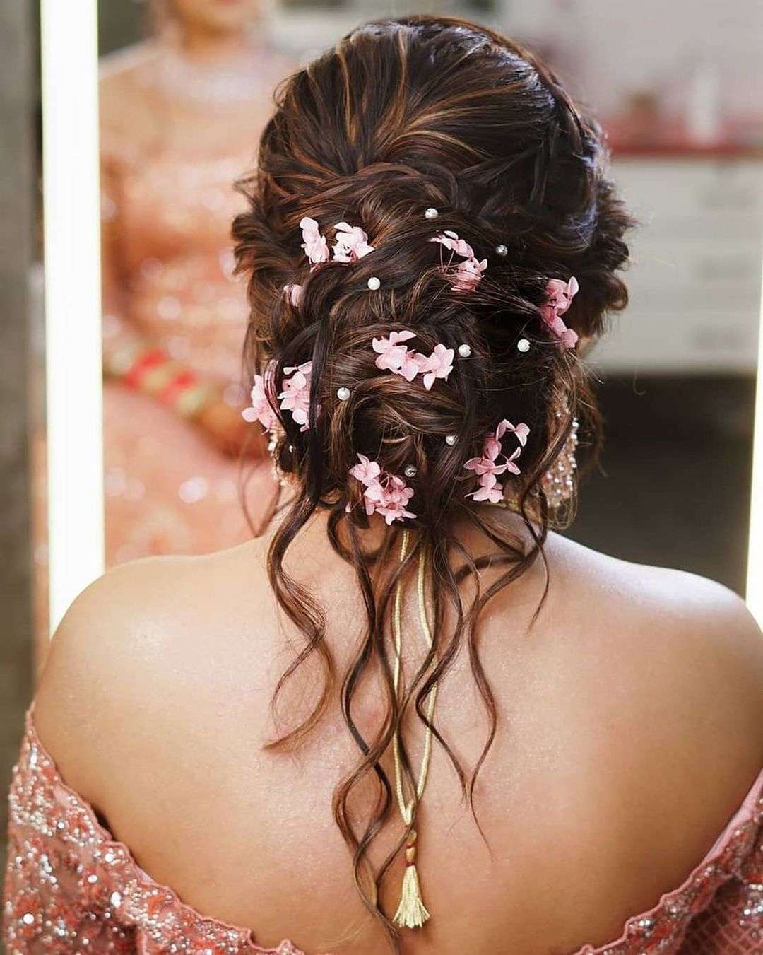 messy low bun with pink flowers indian wedding updo via weddingsdecoded