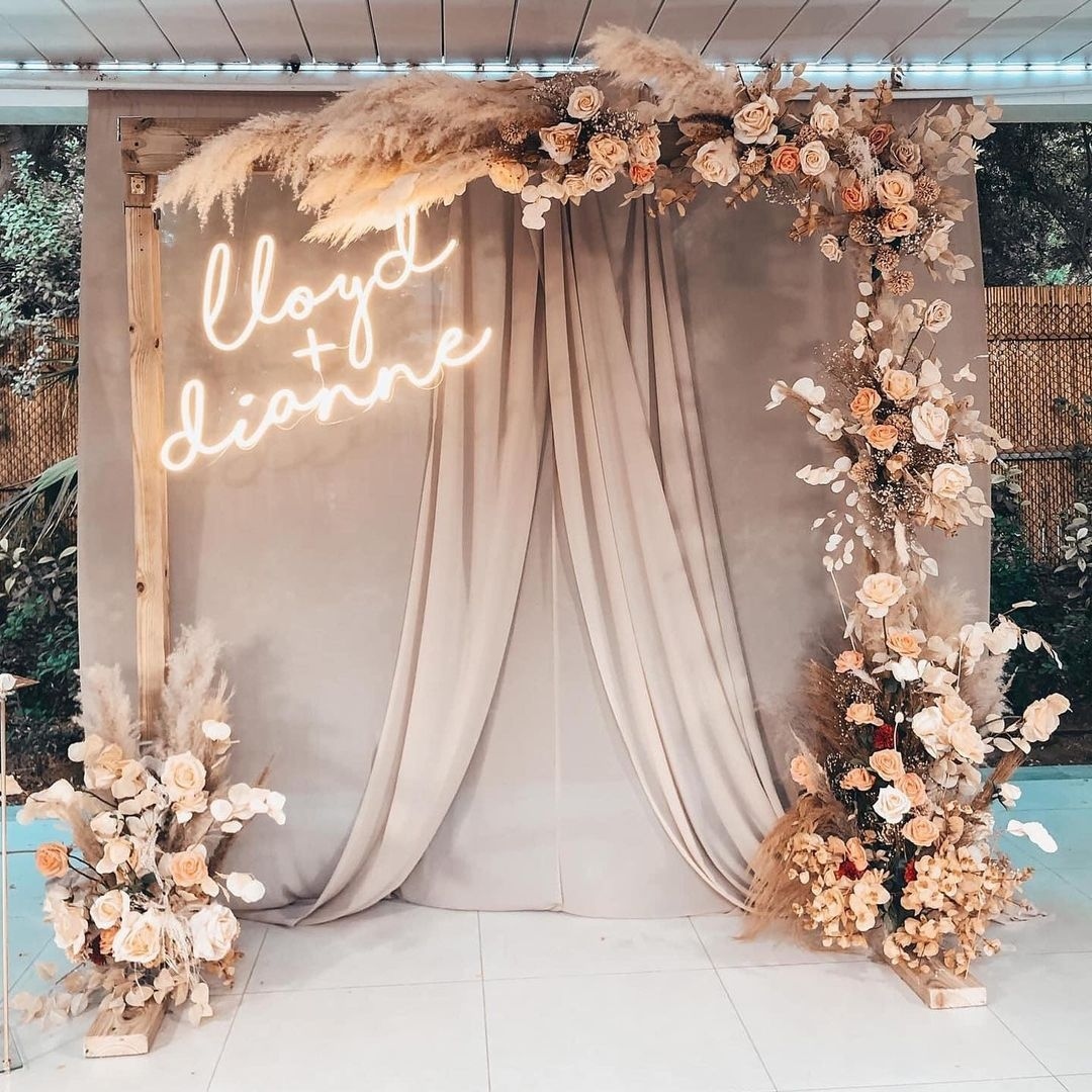 rustic beige pampas grass drapes wedding arch backdrop with neon signs via withjoy