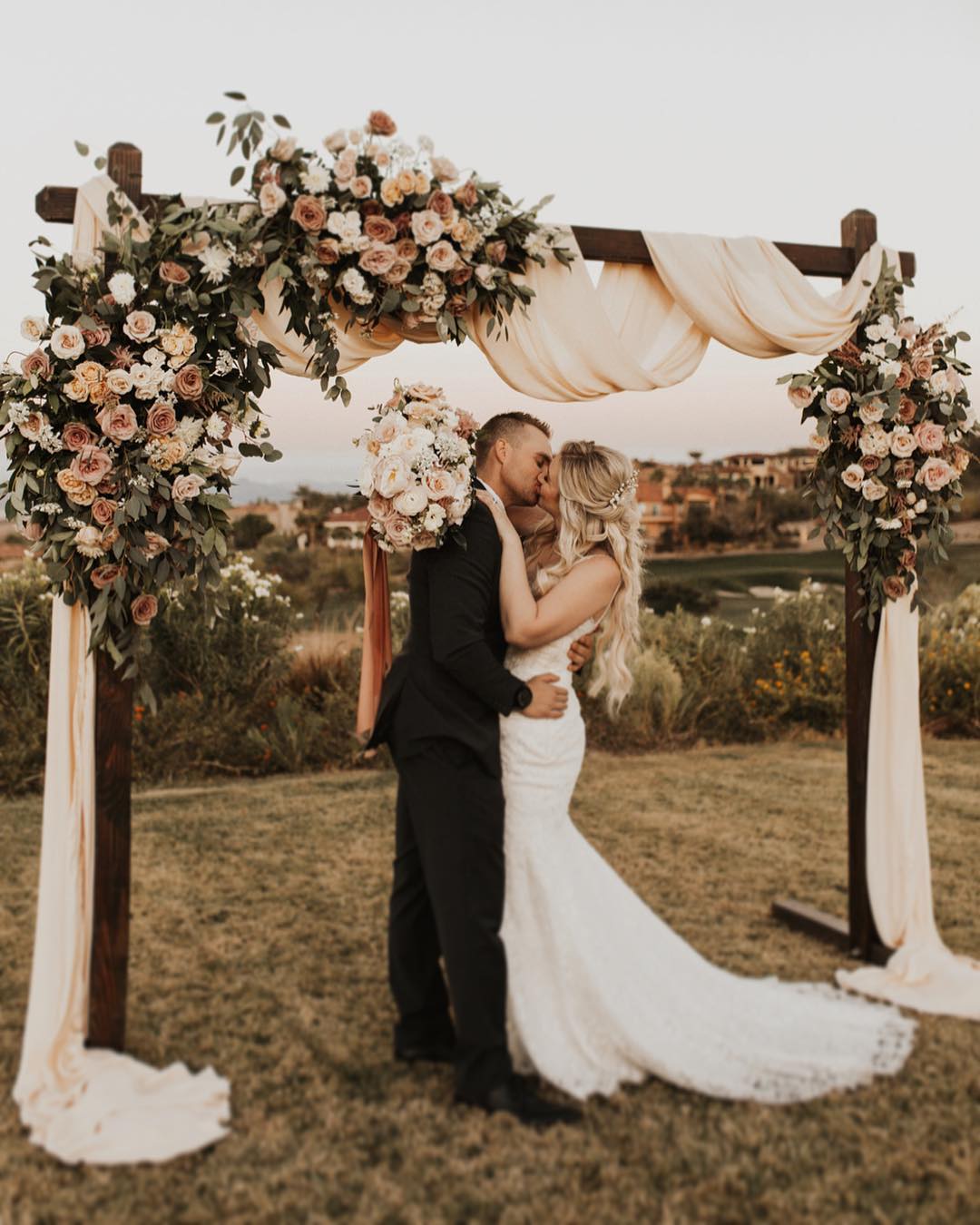 rustic dusty rose wooden wedding arch with roses and fabric drapes