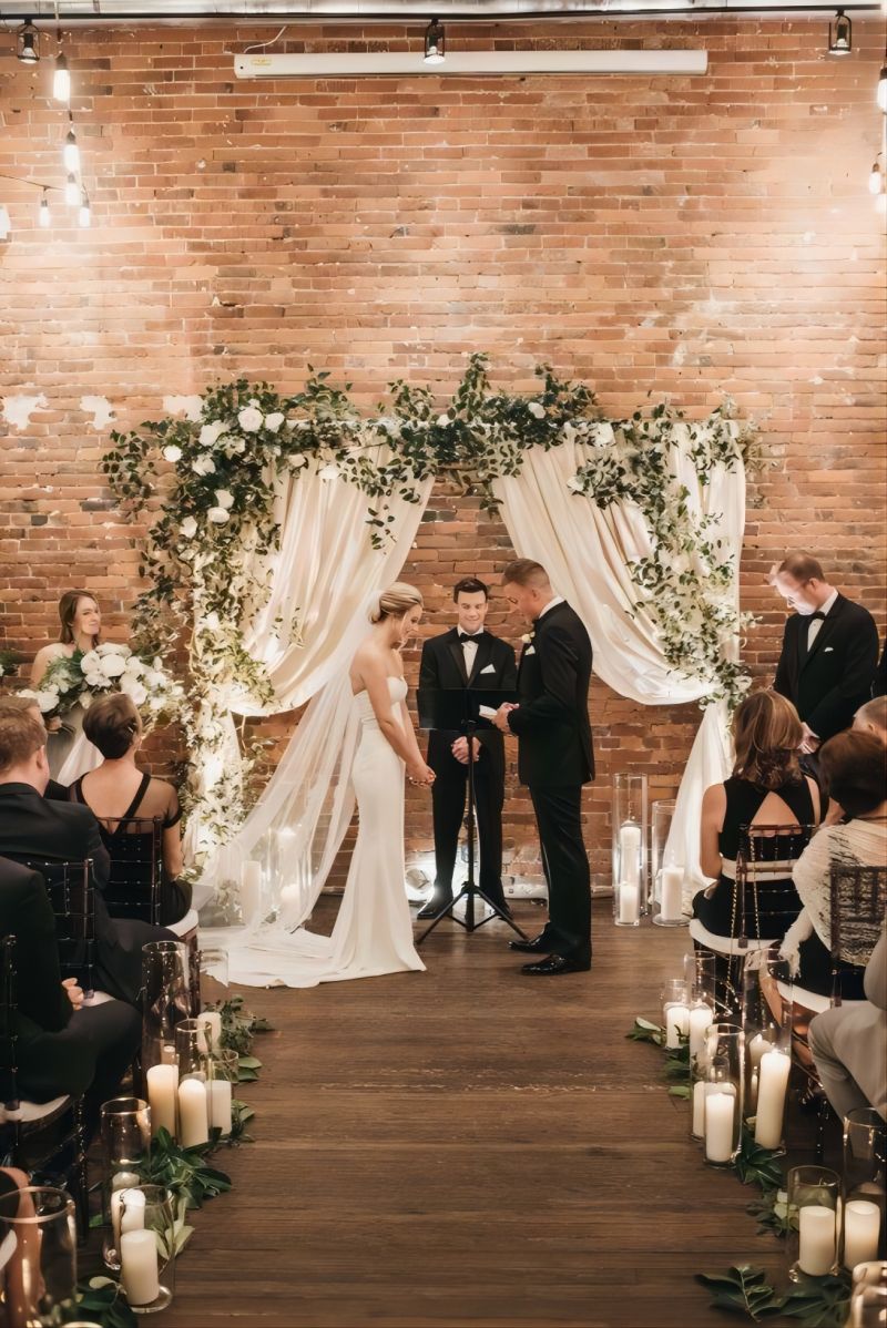 rustic indoor wedding arch with drapes and greenery