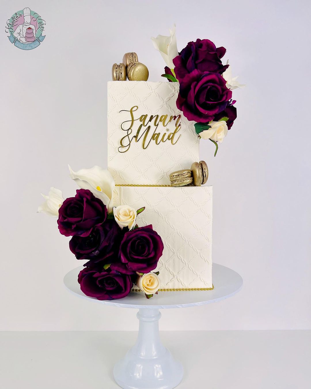 white square wedding cake with burgundy artificial flowers and mirror name sign via khalidskakes