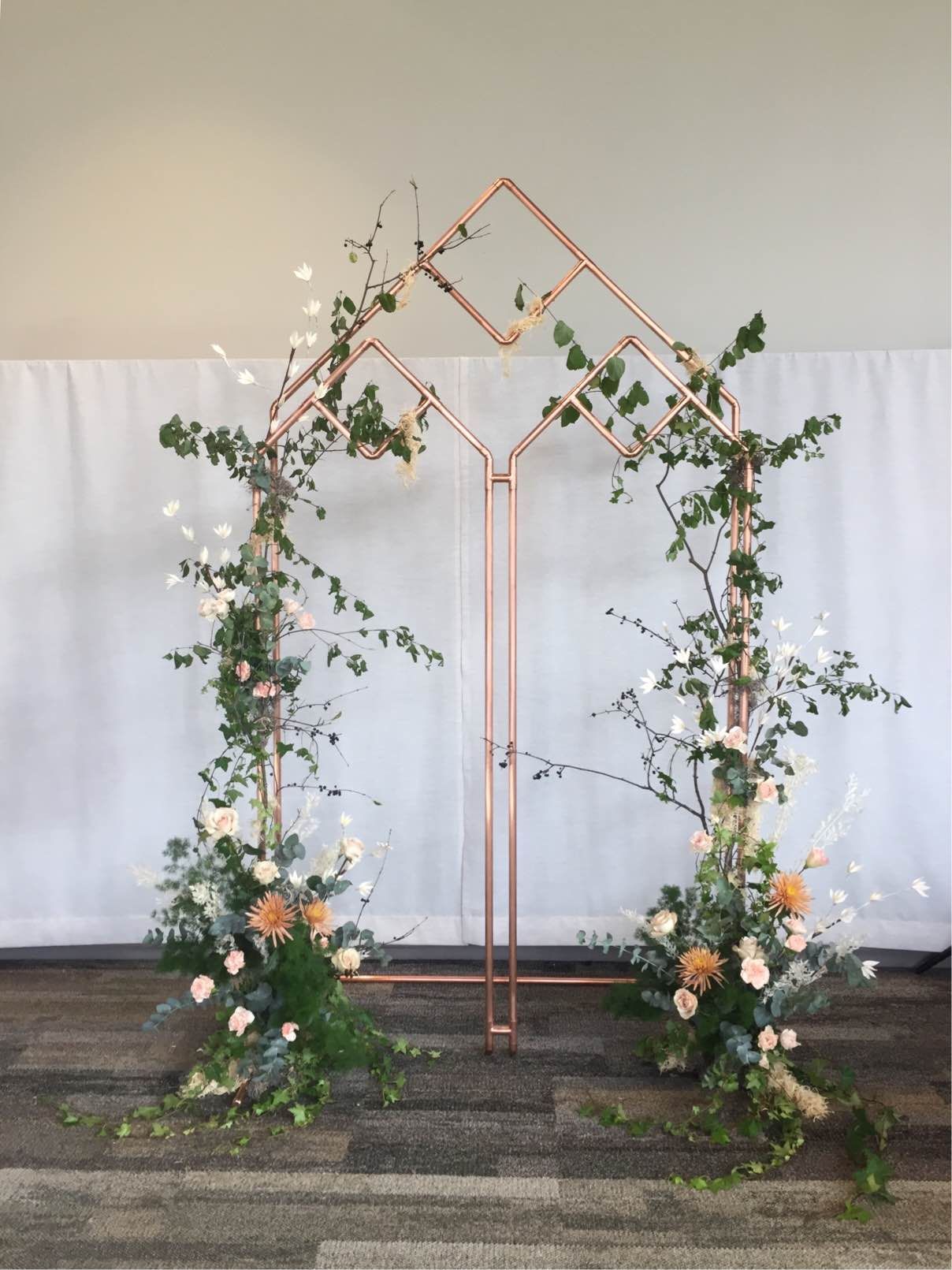 copper metal wedding arch with greenery